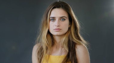 Gri arka planda stüdyo çekimi portresi. Güzel, ciddi, düşünceli, kendine güvenen, model, sarışın, doğal makyajlı, çekici, hayalperest bir bayan.