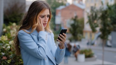 İş kadını, beyaz bayan, cep telefonuyla bakan kadın, kötü haber problemleri hakkında endişe duyuyor. Finansal tebligat hatası, şehirdeki stresten kaynaklanıyor.