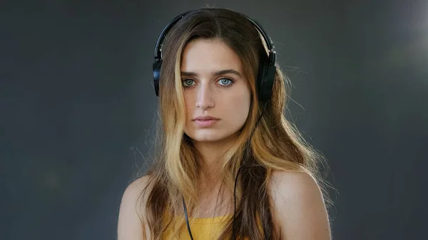 스튜디오 배경의 회색 사진, 아름다운 진지 한 여학생 이 헤드폰을 쓰고 있습니다. 머리에 쓰고 있는 천 년 대금발의 여성 이 이어폰을 끼고 음악을 듣고 — 스톡 사진