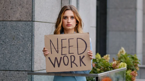 Triste mujer de negocios rubia desempleada se para en la ciudad mirando la cámara sostiene pancarta de cartón necesita trabajo problemas de trabajo preocupados con las finanzas. Pérdida de carrera. Crisis pandémica de desempleo. Pobre chica despedida —  Fotos de Stock