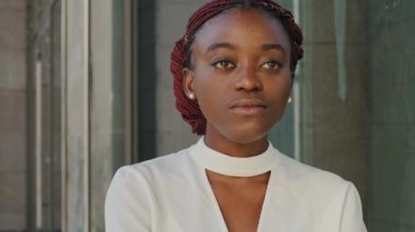 Yakın plan kadın portresi Afro-Amerikan bayan afro kadın iş kadını yüz modeliyle şehirde duruyor arka planda duruyor uzaktan bakarak hayaller kuruyor.