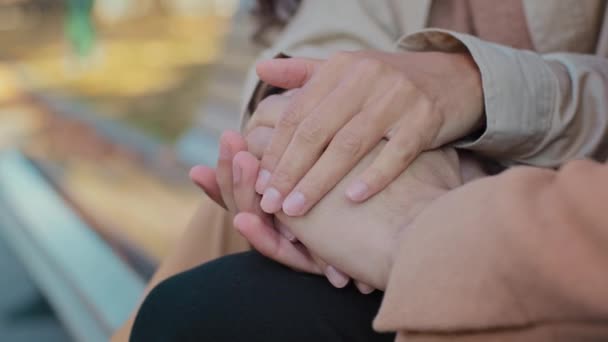 Tutup pasangan muda jatuh cinta berpegangan tangan duduk di bangku dikenali gadis dan pria pada tanggal romantis menekan telapak tangan laki-laki dan perempuan dengan hangat membelai lengan keluarga menikmati waktu bersama-sama di luar ruangan — Stok Video