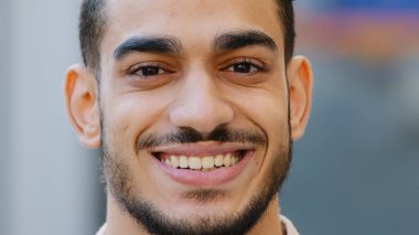 Açık havada erkek portresi, genç İspanyol mutlu, gülümseyen yakışıklı iş adamı şehirde duruyor. Sağlıklı sakallı, Arap bir müşteri. Sağlıklı, dişlek dişli, kameraya bakan bir gülümsemesi var.