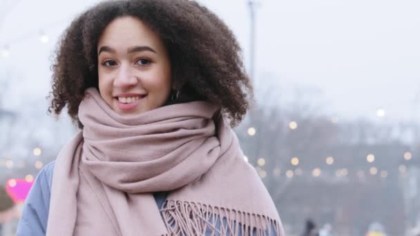 Gros plan portrait de femme en plein air saison froide en hiver. afro-américaine fille dame avec les cheveux bouclés porte élégant modèle d'écharpe rose souriant en regardant autour d'attendre la date de réunion seul — Video