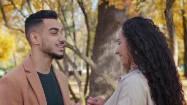 İspanyol erkek ve kız el ele tutuşurken size iyi eğlenceler. Sonbahar parkında caddede dikilen erkek ve kadın gülümseyen aşıklar kucaklaşır. Dışarıda mutlu bir şekilde sarılır.