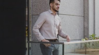 Başarılı dalgın sakallı iş adamı profesyonel uzman patron ofis binasındaki balkon terasına gider. Şehre bakar. Stratejiyi düşünür dinlenmeyi düşünür.