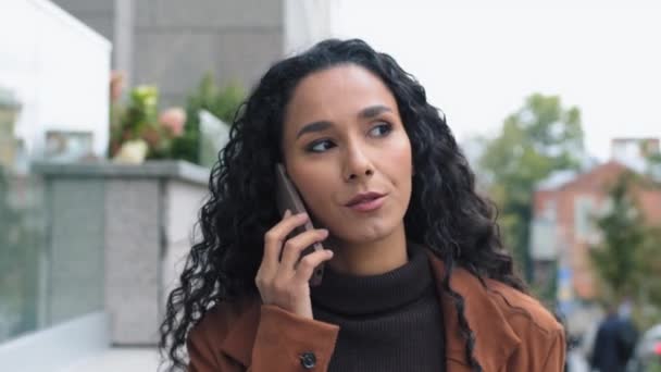 Portret poważny hiszpański arabski latynoski biznes kobieta przedsiębiorca szef odbieranie połączenia spacery w mieście rozmawianie przez telefon komórkowy na ulicy negocjacje zdalna rozmowa ze smartfonem spacery — Wideo stockowe