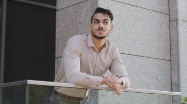 Mutlu, genç, sakallı iş adamının portresi. Patron, yönetici, ofisin balkonunda duruyor. Şehir caddesine bakıyor.