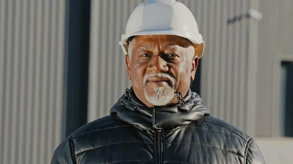 Portrait of elderly african american confident man professional engineer construction worker in safety helmet successful builder contractor foreman standing outdoors site close-up looking at camera — Stockfoto