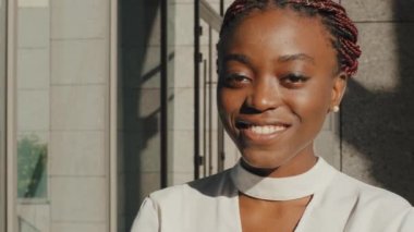 Ön cephede, melez ırktan güzel bir kadın. Yüzü Afro Amerikalı genç bir kadın. Beyaz dişli, arkadaş canlısı gülümseyen bir kız.