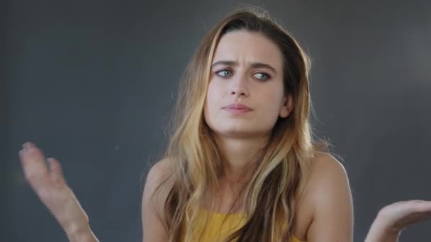 Vrouw portret op grijze achtergrond in studio jong pensive meisje vrouw dame model op zoek naar camera spreidt handen aan zij onbekend houden hoofd van probleem slecht nieuws verlies stress verliezen probleem concept — Stockvideo