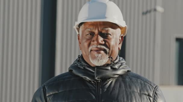 Ritratto di anziano africano americano fiducioso uomo ingegnere professionista lavoratore edile in casco di sicurezza costruttore appaltatore di successo caposquadra in piedi all'aperto sito close-up guardando la fotocamera — Video Stock