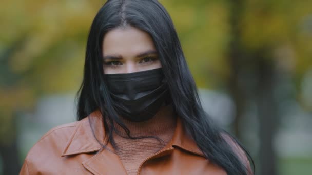 Portrét krásná mladá hispánská žena v ochranné lékařské masky stojící venku při pohledu na kameru vážná dívka bruneta close-up chrání zdraví během koronaviru pandemické karantény19 — Stock video