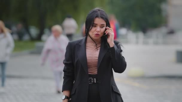 Jeune femme d'affaires excités appels sur téléphone mobile en colère que la personne en retard pour la réunion à l'heure prévue en regardant la montre du poignet avec irritation hispanique fille regarder autour se tient dans le parc près de la chaussée — Video