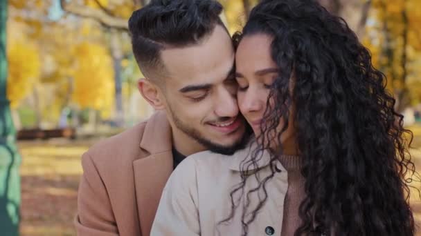 Close-up hispanic couple guy embracing girl romantic date in autumn park lovers enjoy tenderness feeling dreaming of happy future together man hug with woman outdoors loving husband and wife smiling — Stock Video