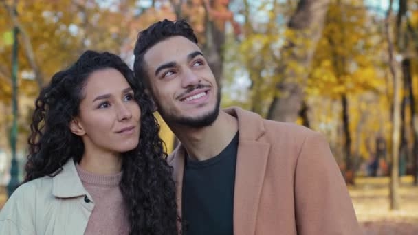 Közelkép boldog spanyol pár randin ősszel park ölelés partnerek nézik egymást nő ölelés érintés jóképű férfi szabadban srác és lány mosoly szorosan szorította arccal néz álmodozva távolba — Stock videók
