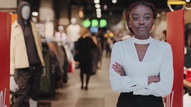 잘 나가는 중소기업 여성 아프리카 계 미국인 여성 여성 옷 판매원 주인 이 쇼핑 센터 입구에 서서 팔을 꼬아 자신있게 일하는 직원을 보고 있습니다 — 비디오