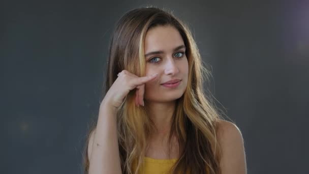 Young lady girl invites contact by phone. Playful happy pretty woman making telephone gesture near head call me sign calling symbol offering communication posing in studio isolated on gray background — Stock Video