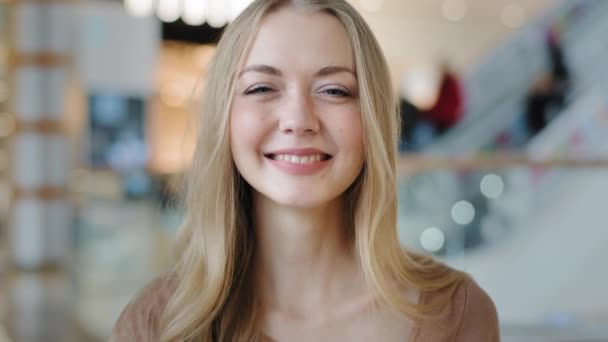 Alışveriş merkezinde gülümseyen mutlu bir kadının yakın plan portresi. Başparmağını kaldırıp kameraya bakıyor. Pozitif hizmet veya ürün tavsiyesi veriyor. — Stok video