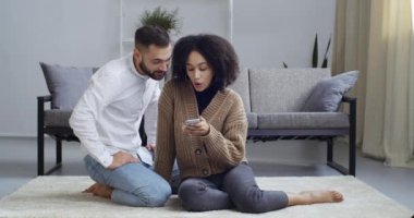 Irklar arası ilişki, beyaz erkek ve tarımsal kız çift evde otururken cep telefonuna bakıyorlar mobilya seçiyorlar internetten sipariş veriyorlar ve kararları tartışıyorlar.