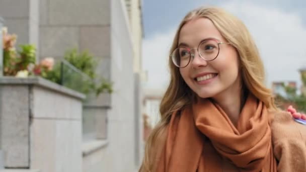 Young woman consumer looking around smiling enjoying good weather girl shopaholic walking outdoors after shopping caucasian female rejoices discount on black friday carries bright bags with purchases — Wideo stockowe