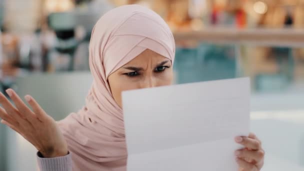 閉校中の若いイスラム教徒の女性が紙の手紙を読んで座って悪いニュース不満イスラム教徒の少女情報にショックを受けた破産通知の解雇は不幸な悲しみ刺激を感じる — ストック動画