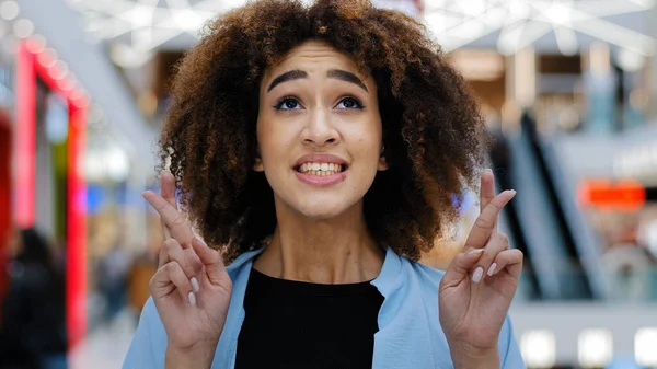 Closeup female portrait young emotional african american woman girl lady lucky with curly hair crossing fingers hoping asking for luck success wish praying looking up hope want victory win indoors — Stockfoto