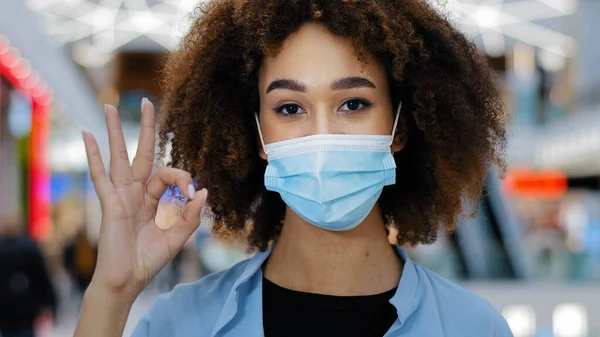 Retrato responsável mulher afro-americana doente senhora menina com cabelo encaracolado olhando para câmera acenando dedo não colocar em máscara protetora médica corretamente mostrando sinal ok, regras de proteção coronavírus — Fotografia de Stock