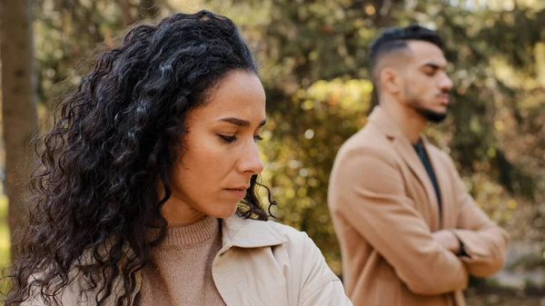 De cerca ofendido molesto rizado chica en segundo plano enojado chico familia riña mujer se aleja de hombre hispano pareja de pie ignorando unos a otros al aire libre conflicto malentendido infeliz mujer sentirse triste — Foto de Stock