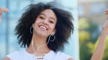 Neşeli genç Afro-Amerikan milenyum kadını yükseğe zıplamaktan, silah sallamaktan ve elinde akıllı telefonuyla havada dans etmekten, modern şehir binasının arka planına gülüp eğlenmekten hoşlanıyor..