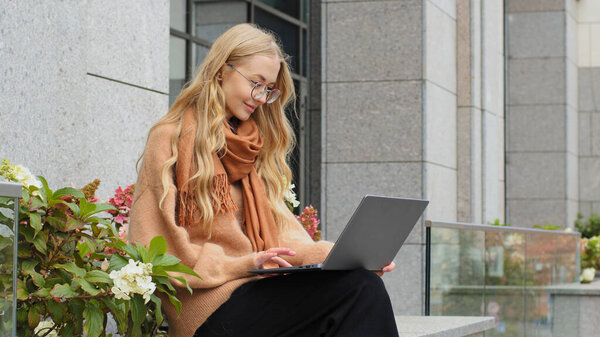Successful attractive business woman working on laptop in city caucasian girl student e-learning outdoors lady typing sitting on terrace female freelancer chatting with client using wireless computer