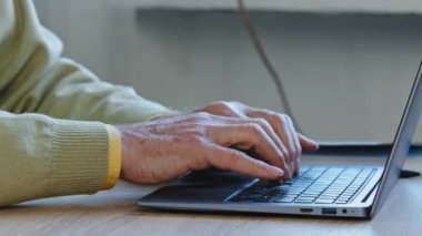 Unrecognizable mature adult man writes text on portable wireless computer indoors close-up hands elderly male typing on laptop keyboard unknown caucasian businessman working online using internet app