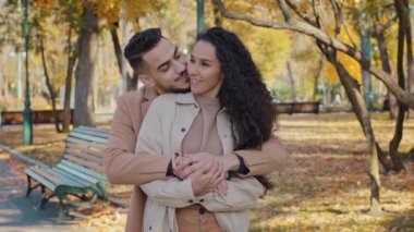 Hispanic family hugging standing in autumn park young couple smiling talking romantic date outdoors guy and girl enjoying conversation embrace planning joint happy life feeling love enjoy each other