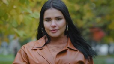 Portre İspanyol kadın dışarıda duruyor. Ciddi kız kameraya bakıyor. Elinde işaret parmağı var. Ağız kenarında.