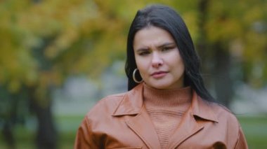 Headshot overweight young woman stands outdoors looking at camera hispanic angry girl showing thumbs down disapproval sign disagreement refusal demonstrates low grade gesture dislike negative attitude
