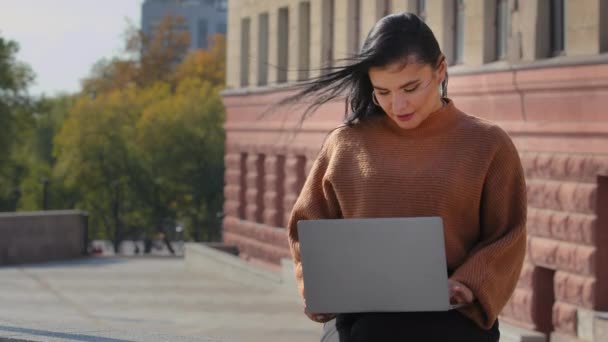 Jeune étudiante ciblée femme d'affaires pigiste travaillant sur ordinateur portable e-learning en plein air hispanique fille dactylographie écrit un message électronique en utilisant un dispositif informatique sans fil femme mignonne sourire lit de bonnes nouvelles — Video