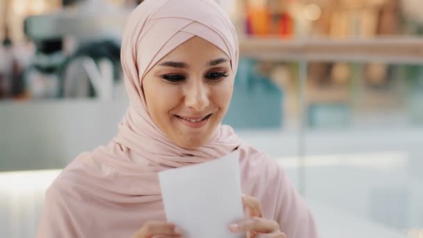 Happy young arab woman reading paper letter smiling enthusiastic muslim girl rejoices of good news entered university exam results bank loan approval salary increase career advancement got dream job — стоковое видео