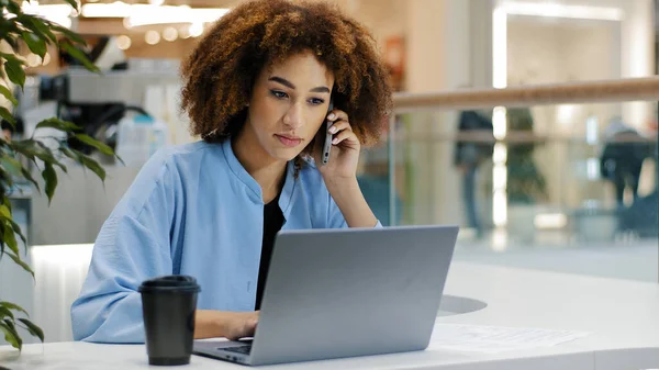 Afro americano occupato affari donna freelancer ragazza manager capo femmina leader lavoratore parlare da cellulare risposta chiamata scrive note di lavoro con laptop negoziati online multitasking concetto — Foto Stock