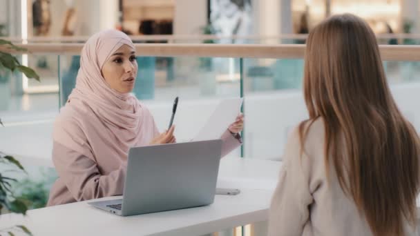 Two young girls sitting at table friendly muslim woman financial advisor explaining benefits contract manager sales agent lawyer consults with client business meeting legal consultation negotiation — Stockvideo