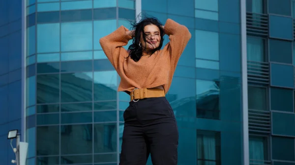 Happy carefree young woman brunette model actively dancing outdoors on city building background funny joyful hispanic girl student smiling rhythmically moving winner dance enjoying weekend freedom — Zdjęcie stockowe
