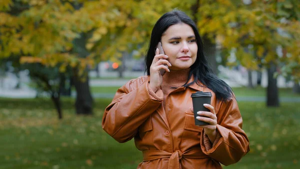 Młoda kobieta rozmawiająca przez telefon ze swoim chłopakiem zgadza się spotkać wesołą piękną dziewczynę odpoczywającą w weekend w parku pijącą pyszną gorącą kawę o miłym czasie uśmiechu przyjemna rozmowa na komórce — Zdjęcie stockowe