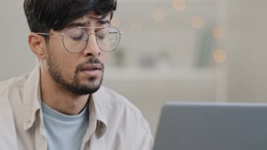 Close-up arab business man student male bearded boss leader with glasses guy works with laptop problems suffers from headache massages head feeling stress solves difficult trouble searching solution