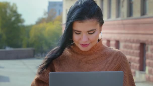 Close-up young businesswoman freelancer sitting outdoors working on laptop happy hispanic girl student studying remotely chatting online smiling looking at camera showing thumb up approval gesture — Stock Video