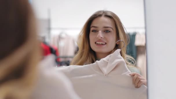 Alegre carefree feliz jovem comprador shopaholic mulher sorrindo senhora consumidor fêmea loira experimentando no novo suéter roupas na loja em casa perto de espelho compras beleza descontos tendência estilo — Vídeo de Stock