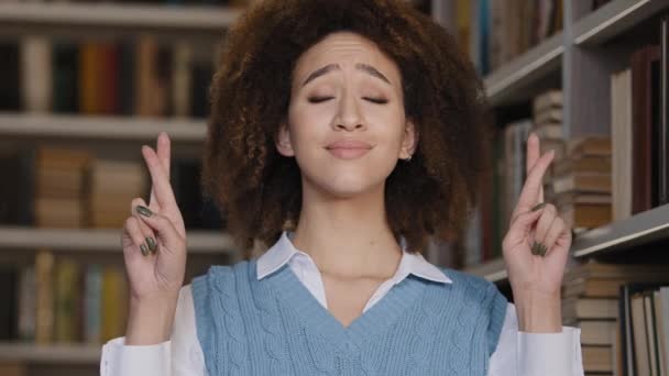 Close-up young african american woman standing indoors crossing fingers making gesture of hope cute girl student makes wish with closed eyes before exam expects positive result asks good luck victory — Wideo stockowe