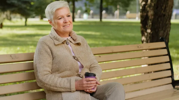 Gerimpeld gezicht van 60-er jaren gelukkige oudere vrouw buiten in het park kijken opzij met een brede glimlach, tandheelkundige implantaten en prothesen tevreden klant portret, verzekering voor ouderen, natuurlijke schoonheid concept — Stockfoto