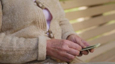 Unhappy anxious elderly woman sitting on bench outdoors holding pile of dollar bills, paper money, counting cash. European old lady upset about low payout income in crisis. Currency exchange concept