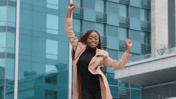 Happy excited beautiful young african american business woman dancing alone outdoor on modern building background celebrate reward successful career corporate promotion enjoy victory dance concept — ストック動画