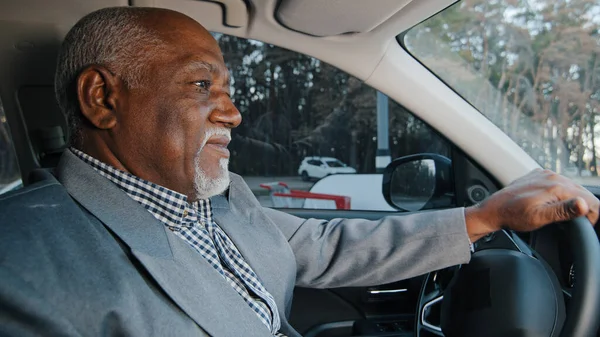 高齢のアフリカ系アメリカ人ビジネスマンは、道路上で自動車を運転経験豊富な自信のあるドライバを慎重に道路の旅を見て成熟した男が車を購入テストドライブを楽しむ快適な乗り心地 — ストック写真