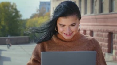 Kız serbest yazar dışarıda dizüstü bilgisayarda işe yarar bilgi arıyor ya da internet kullanıcısı üzerinde çalışıyor. Yeni uygulama bilgisayar teknolojisiyle gülümsüyor. Tamam işaret işareti onayını gösteriyor.